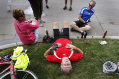 Bill Voss, of St. Louis, Mo., lies down on a corner as his wife Debbie Voss and son-in-law Barney Horrell, of Roanoake, VA, look on as RAGBRAI arrived in Indianola, Tuesday, July 21, 2009. (John Gaps III/The Register)